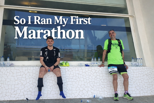 Two exhausted but smiling runners resting after finishing their first marathon, with bottles of water beside them and the title “So I Ran My First Marathon” overlaid.